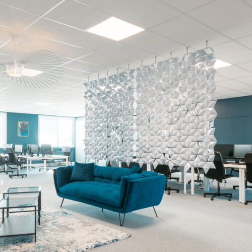 Design de escritório em plano aberto com divisória suspensa Facet em azul-claro criando privacidade entre o lounge e os espaços de trabalho em Mérignac
