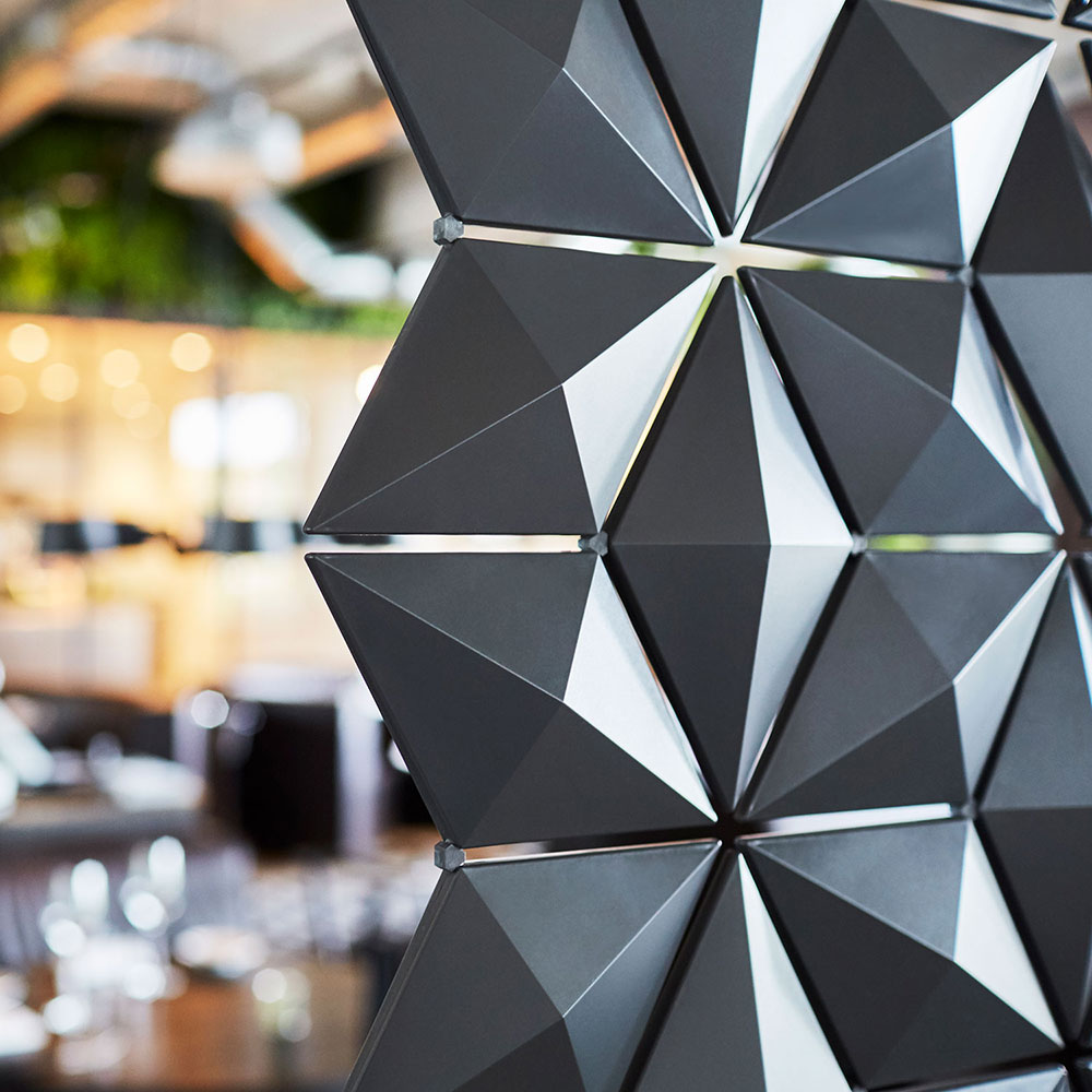 Geometric restaurant and bar partition with rotating facets creating dynamic light and shadow