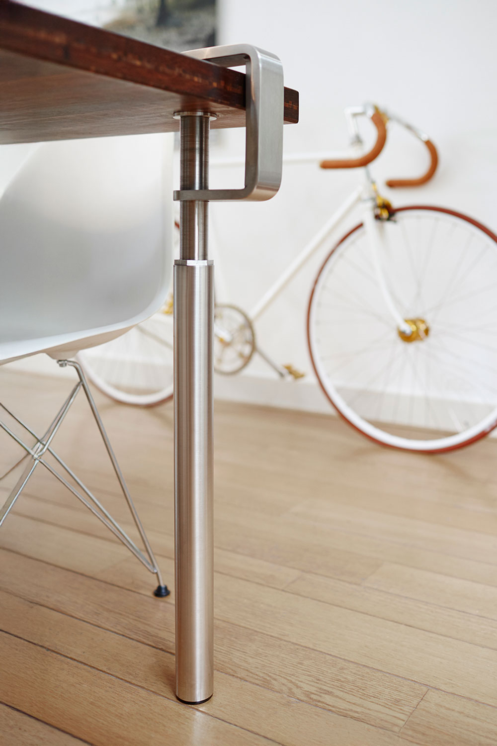 Grip stainless steel table leg by Bloomming clamped to wooden tabletop.