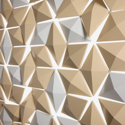 Nahaufnahme des Facet Raumteilers mit beigen und weißen geometrischen Elementen, die ein dreidimensionales Muster bilden.